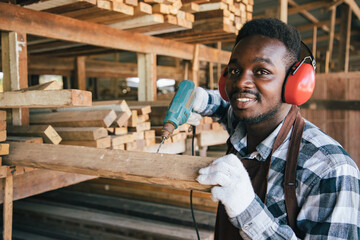 Africa American carpenter using electric drill of house wooden interior accessories for further...