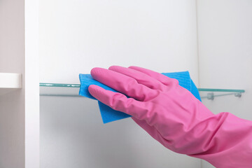 Hand in rubber protective glove cleaning shelves in cupboard home. Spring, regular or general...