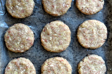 Raw cutlets are on parchment paper and on a baking sheet