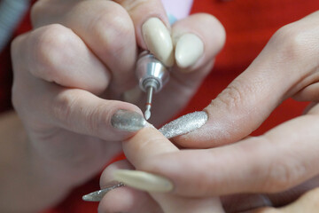 female manicure, master treats nails with an electric nail file