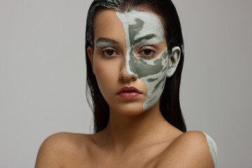 Portrait of a beautiful tanned girl with clay on her face and body. Art photography. Gentle skin and hair care, spa and makeup