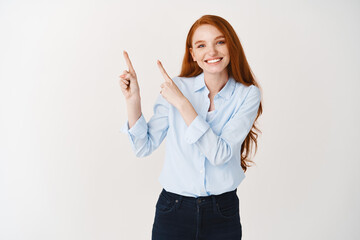 Image of beautiful woman with ginger hair and pale skin wearing office blouse and pointing upper...