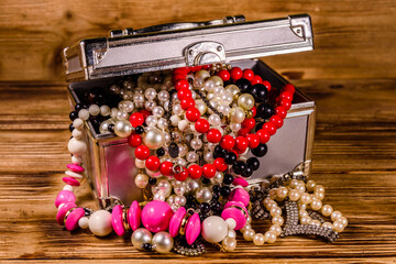 Aluminium case full of different jewelry on wooden table