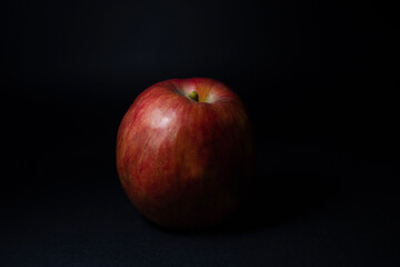 Red apple on a black background close-up.
