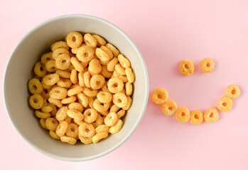 Bowl of breakfast cereal in pink background. Healthy Cereal Rings. Space for text. Top view. Flat lay.