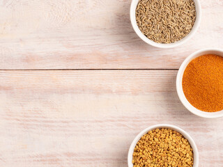 Spice red chili pepper, cumin, fenugreek in a white bowl on a light wooden background