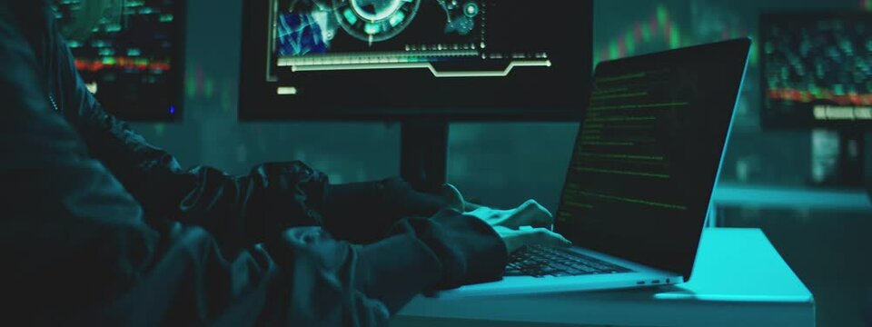 Female Hacker working on laptop at night in the modern workspace. Female Hands are typing a code at keyboard or hacking a website.