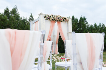 Place for wedding ceremony in white color .White square wedding arch with bouquets of pastel roses in the forest.
