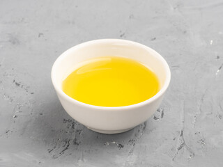 Honey in a white bowl on gray concrete background
