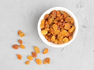 Raisins in a white bowl on gray concrete background
