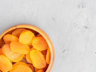 Dried apricots in a wooden bowl on gray concrete background. Healthy eating concept