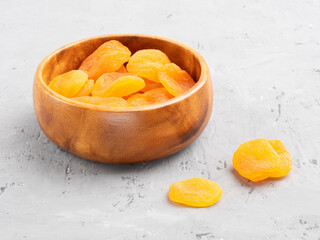 Dried apricots in a wooden bowl on concrete background