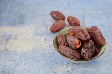 Fresh raw organic Medjool dates on blue background, selective focus, negative space
