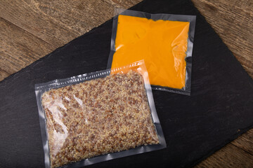 Vacuum sealed packaging with sauce and buckwheat on black slate
