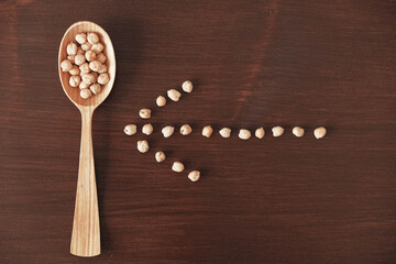 Raw chickpeas in a wooden spoon on a wooden background. Top view. Copy, empty space for text