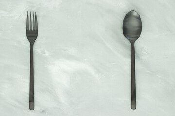 Black fork and spoon on gray background 