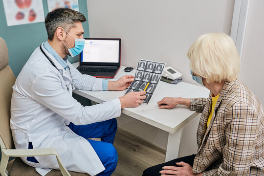 Male Doctor Analyzing For Older Patient A CT Scan Of Her Lungs. Pneumonia, Coronavirus, Lung Disease