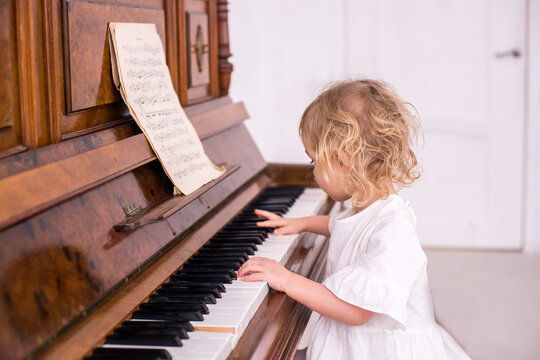 Litle girl playing piano enjoying time practicing music at home