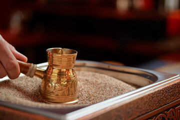 Traditional turkish coffee in cezve prepared on hot sand.