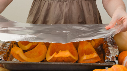 Pumpkin slices close up on a prepared baking pan covered with aluminum foil. Baking pumpkin, step...