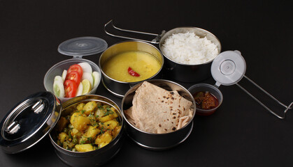 Typical Stainless steel Lunch Box or Tiffin with Maharashtrian food menu Chapati OR Roti, Plain Dal Tadka, White Rice Potato sabji with salad and pickle