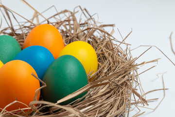 Colorful Easter eggs in nest on a white background.
