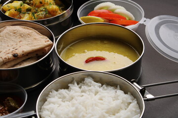 Typical Stainless steel Lunch Box or Tiffin with Maharashtrian food menu Chapati OR Roti, Plain Dal Tadka, White Rice Potato sabji with salad and pickle