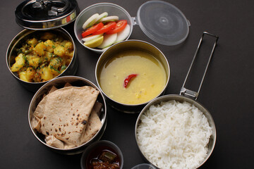 Typical Stainless steel Lunch Box or Tiffin with Maharashtrian food menu Chapati OR Roti, Plain Dal Tadka, White Rice Potato sabji with salad and pickle