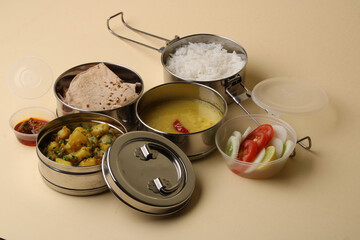 Typical Stainless steel Lunch Box or Tiffin with Maharashtrian food menu Chapati OR Roti, Plain Dal Tadka, White Rice Potato sabji with salad and pickle