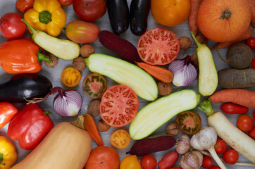 Mix of various fresh organic vegetables: carrots, garlic, eggplants, zucchini, beet, tomatoes on the gray background. Raw ingredients for veggie healthy or diet dish