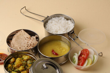 Typical Stainless steel Lunch Box or Tiffin with Maharashtrian food menu Chapati OR Roti, Plain Dal Tadka, White Rice Potato sabji with salad and pickle