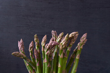 Fresh green asparagus on black wooden background with copy space. Close up view