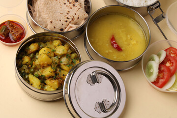 Typical Stainless steel Lunch Box or Tiffin with Maharashtrian food menu Chapati OR Roti, Plain Dal Tadka, White Rice Potato sabji with salad and pickle