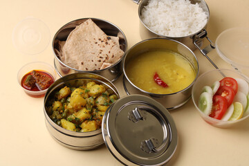 Typical Stainless steel Lunch Box or Tiffin with Maharashtrian food menu Chapati OR Roti, Plain Dal Tadka, White Rice Potato sabji with salad and pickle