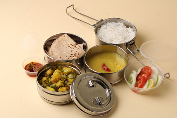 Typical Stainless steel Lunch Box or Tiffin with Maharashtrian food menu Chapati OR Roti, Plain Dal Tadka, White Rice Potato sabji with salad and pickle