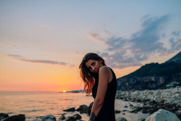 Fototapeta na wymiar Pretty brunette girl looking at sunset on sea 