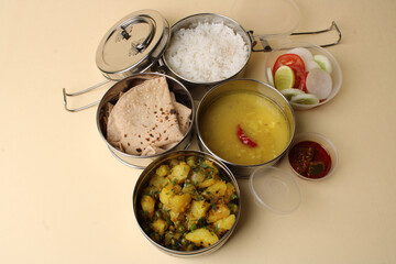 Typical Stainless steel Lunch Box or Tiffin with Maharashtrian food menu Chapati OR Roti, Plain Dal Tadka, White Rice Potato sabji with salad and pickle