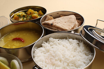 Typical Stainless steel Lunch Box or Tiffin with Maharashtrian food menu Chapati OR Roti, Plain Dal Tadka, White Rice Potato sabji with salad and pickle