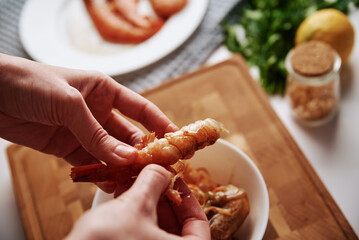 Woman cleaning shrimps for cooking. Process of hands peel shrimps shell