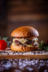 Craft beef smash burger with cheese, bacon and sauce on wooden background