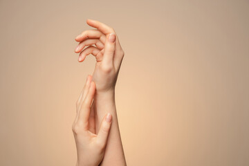 A woman's hands close up, on a beige background.