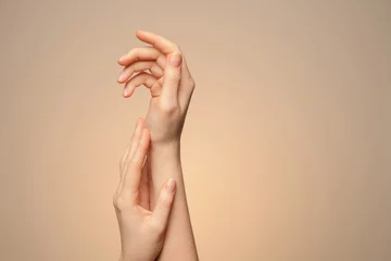 A woman's hands close up, on a beige background.