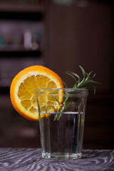 Gin in a glass. Garnished with a slice of orange and rosemary.