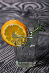 Gin in a glass. Garnished with a slice of orange and rosemary.