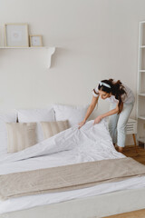 Fototapeta na wymiar Young beautiful woman making bed.