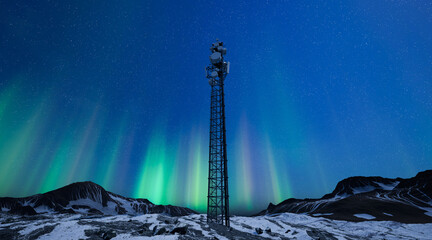 Telecommunication tower with 5G cellular network antenna on night winter landscape with aurora...