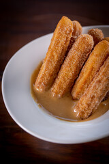 Churros sticks with caramel in a wooden background