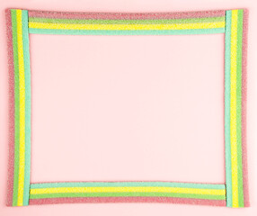 Frame made of gummy candies on pastel pink paper background. Mock up for your congratulations text or note