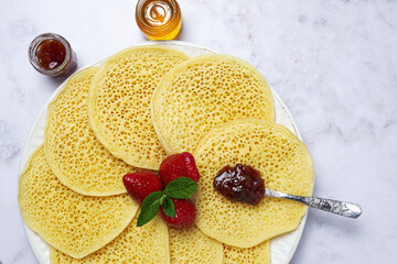 Homemade traditional moroccan baghrir with honey, strawberries and mint from above