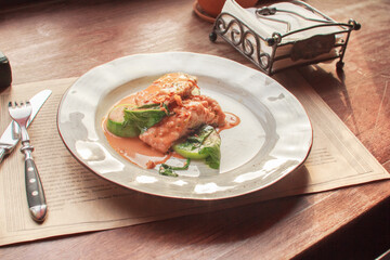Healthy lunch, dinner on sunny day in a restaurant or café. Stewed Fish fillets with in Sauce  with  Zucchini and Spinach  on Wooden background . Healthy fish menu. Side view, stock photo